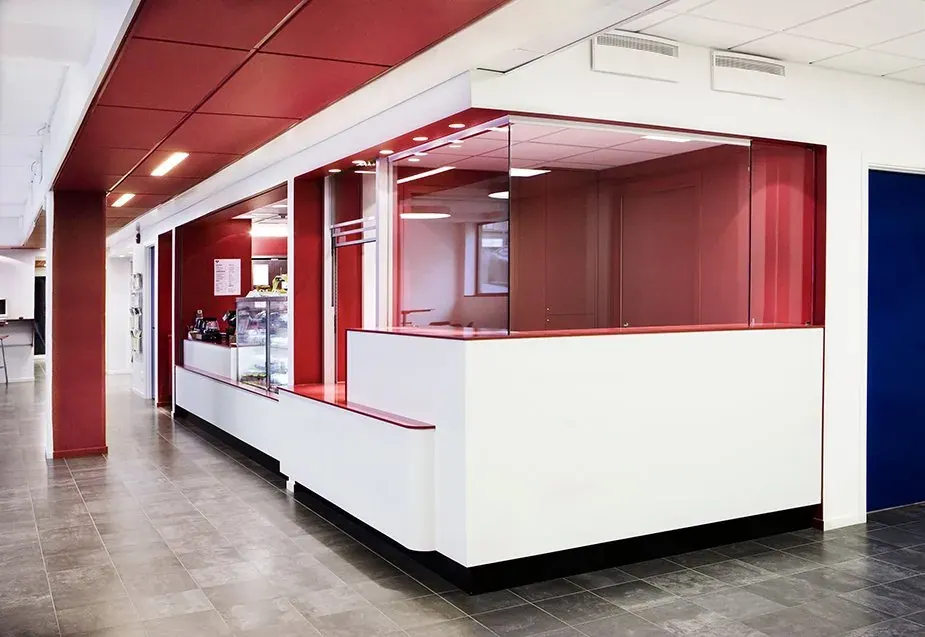 Vit och röd receptionsdisk med glasskärm i en offentlig entréhall